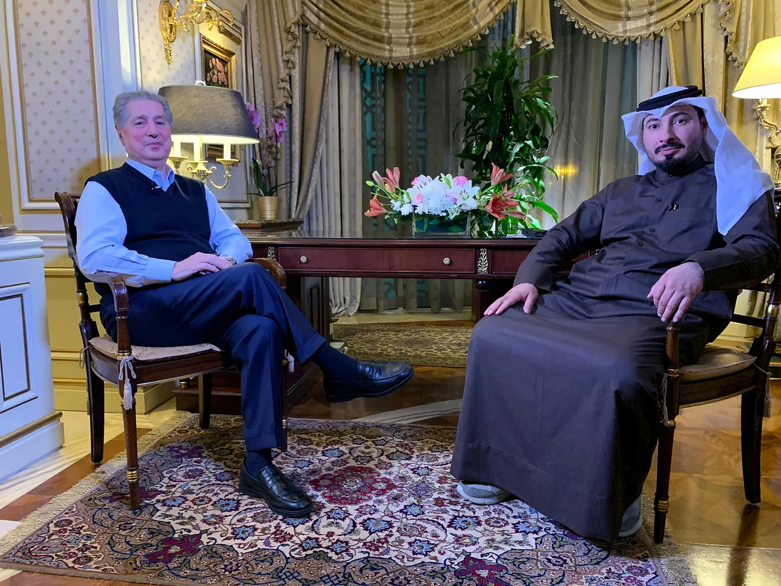 Two people seated in conversation in an indoor reception room